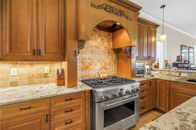 kitchen with light stone countertops, backsplash, high end range, and decorative light fixtures