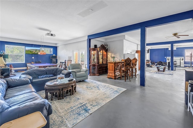 living area with pool table, a ceiling fan, concrete flooring, and a textured ceiling