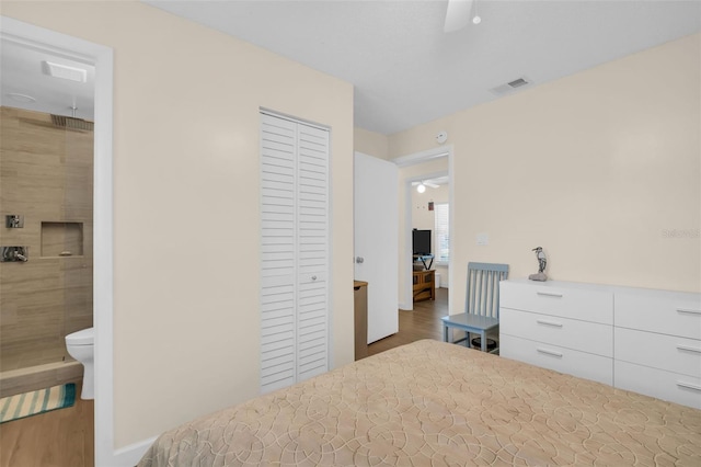 bedroom featuring a closet, baseboards, visible vents, connected bathroom, and wood finished floors