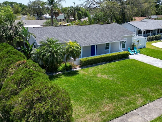 ranch-style home featuring covered porch, fence, driveway, a front yard, and a shingled roof