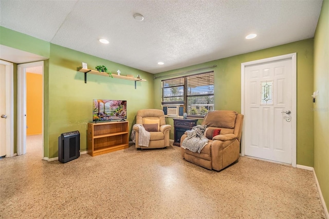 living area with recessed lighting, a textured ceiling, and baseboards