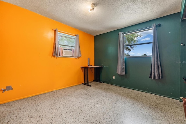 spare room with baseboards, cooling unit, speckled floor, and a textured ceiling