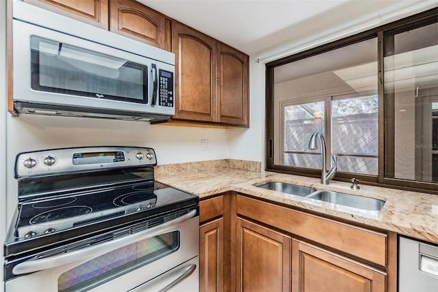 4002 Cypress Ct Unit 4002, Tampa, FL 33618 - kitchen featuring a sink, appliances with stainless steel finishes, brown cabinets, and light stone countertops