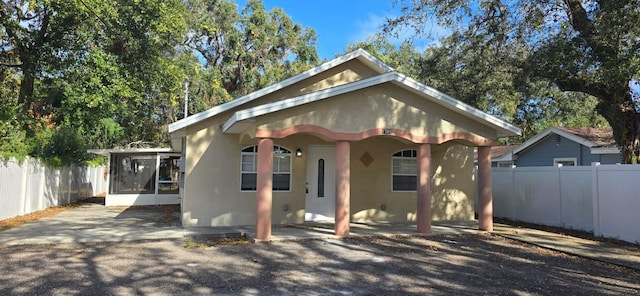 view of front facade featuring fence, stucco siding, and a sunroom
