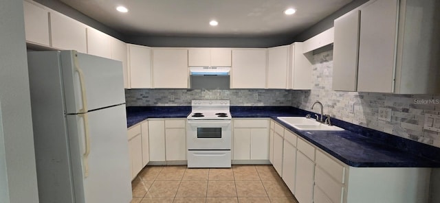 kitchen with dark countertops, white appliances, under cabinet range hood, a sink, and light tile patterned floors
