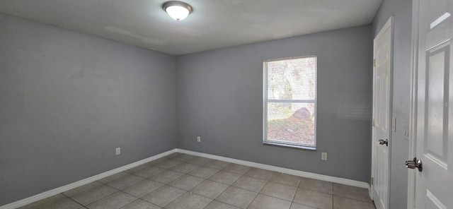 empty room with baseboards and light tile patterned floors