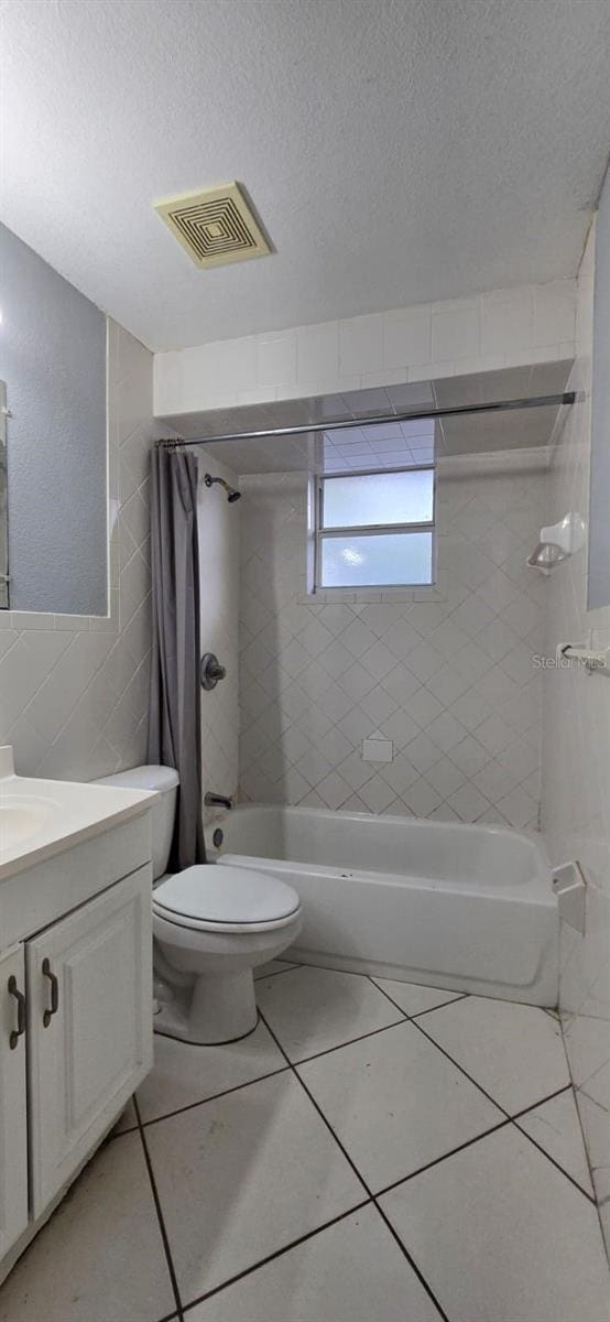 bathroom with a textured ceiling, shower / bath combination with curtain, visible vents, vanity, and toilet