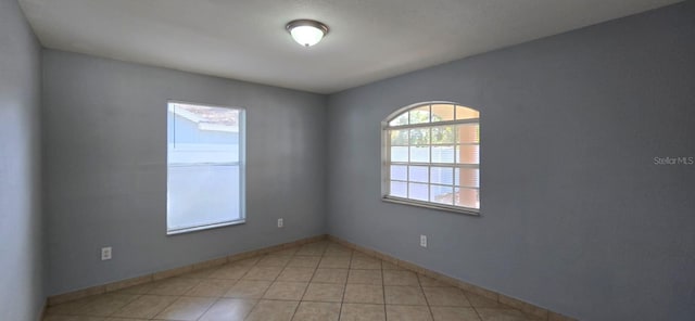 empty room with baseboards and light tile patterned floors