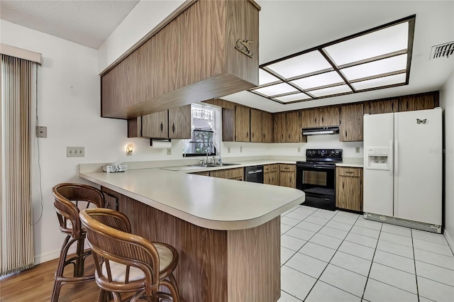 883 N Hollywood Cir, Crystal River, FL 34429 - kitchen featuring light countertops, black appliances, a peninsula, a breakfast bar, and under cabinet range hood
