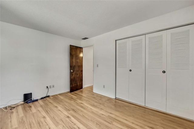 883 N Hollywood Cir, Crystal River, FL 34429 - unfurnished bedroom with visible vents, a closet, baseboards, a textured ceiling, and light wood finished floors