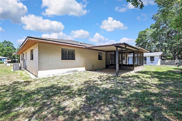 883 N Hollywood Cir, Crystal River, FL 34429 - rear view of property featuring central AC, fence, stucco siding, a sunroom, and a yard