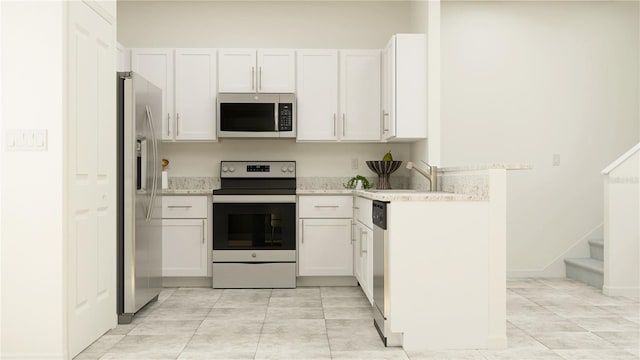 kitchen with a sink, light stone counters, white cabinets, and stainless steel appliances