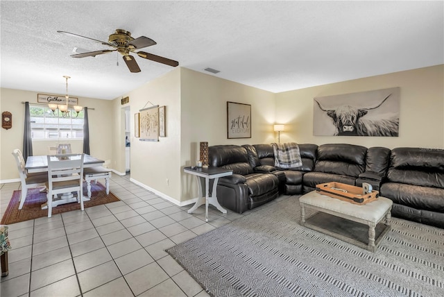 living area with light tile patterned flooring, baseboards, ceiling fan with notable chandelier, and a textured ceiling