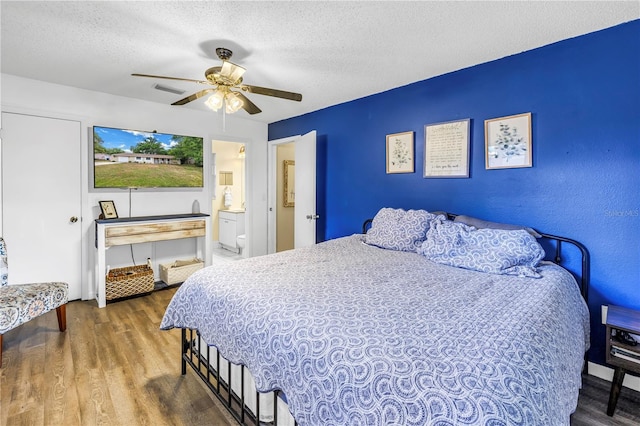 bedroom featuring a textured ceiling, ceiling fan, wood finished floors, and ensuite bathroom