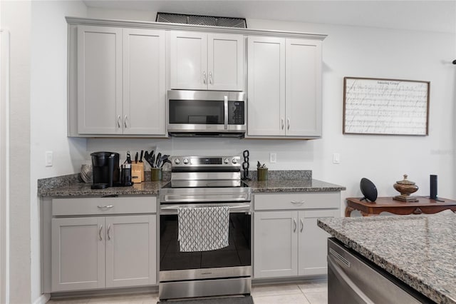 kitchen featuring stainless steel appliances, visible vents, gray cabinetry, and dark stone countertops