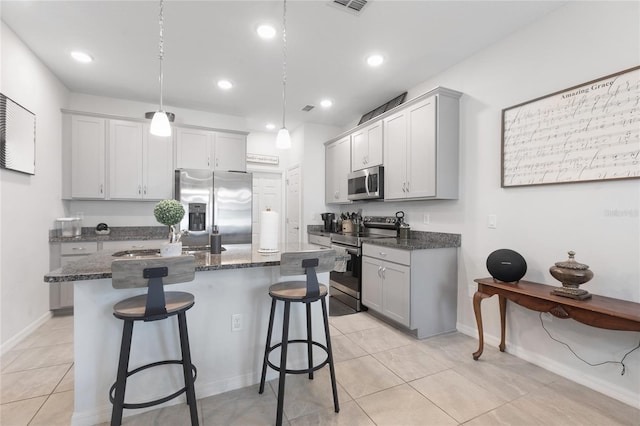 kitchen with a breakfast bar area, a kitchen island, a sink, dark stone counters, and stainless steel appliances