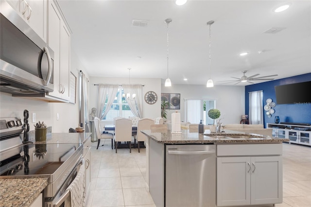 kitchen featuring a sink, light tile patterned floors, stone countertops, and stainless steel appliances