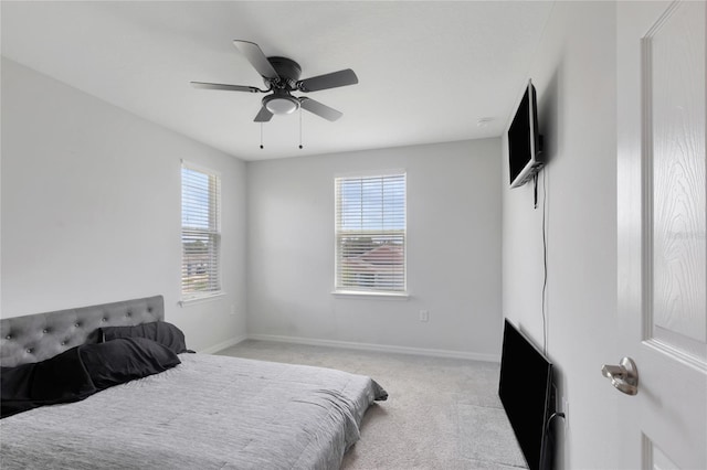 bedroom with a ceiling fan, baseboards, and light colored carpet