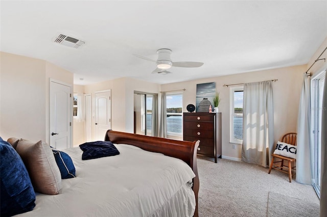 bedroom featuring a ceiling fan, visible vents, multiple windows, and carpet