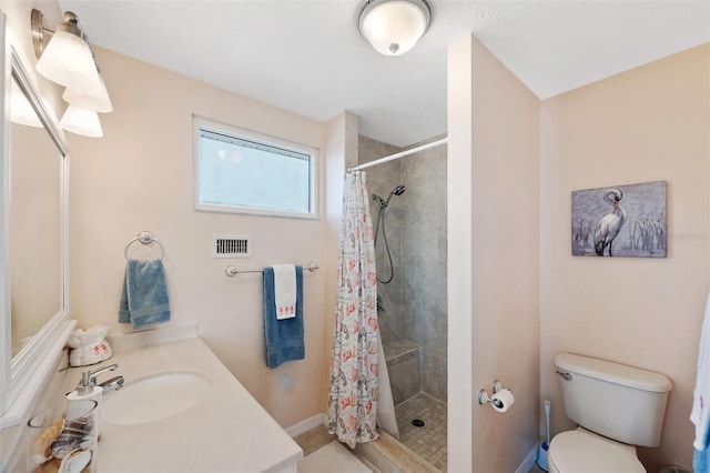 bathroom featuring visible vents, a stall shower, vanity, baseboards, and toilet