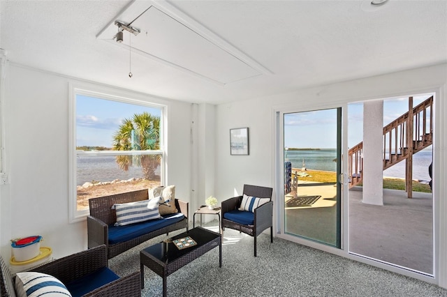 sitting room with carpet floors, a water view, track lighting, and attic access