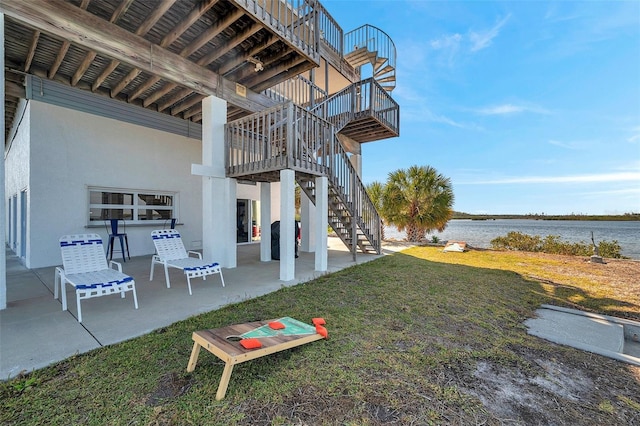 view of yard featuring a water view, a patio area, and stairway
