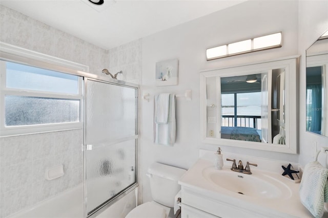 bathroom featuring vanity, plenty of natural light, combined bath / shower with glass door, and toilet