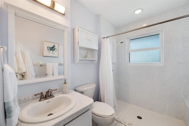 full bathroom with toilet, a tile shower, and vanity