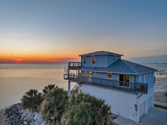 view of front of house featuring a garage, stucco siding, a water view, concrete driveway, and metal roof