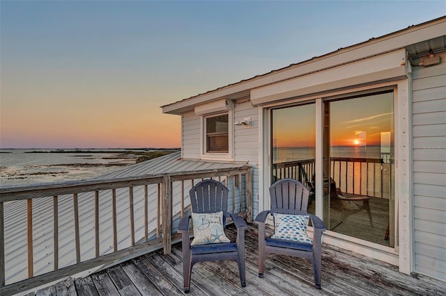 deck at dusk featuring a water view