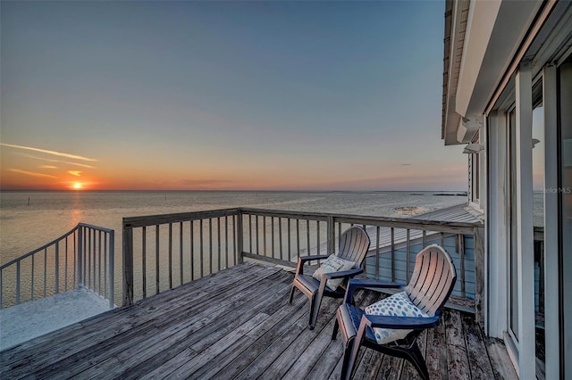 deck at dusk featuring a water view