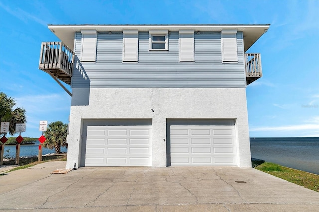 view of front of property with an attached garage, stucco siding, a balcony, and driveway