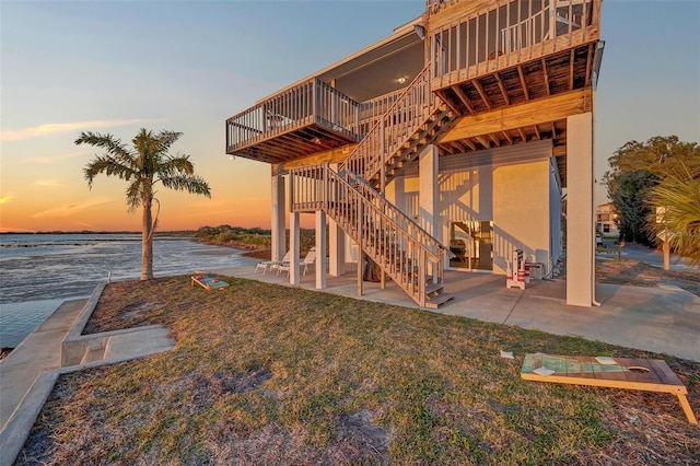 back of property with a patio area, a deck with water view, and stairway