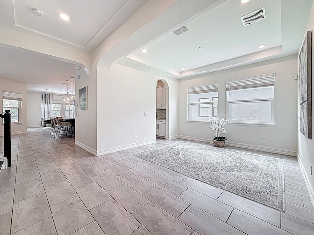 18203 Pine Hammock Blvd, Lutz, FL 33548 - empty room with a tray ceiling, arched walkways, recessed lighting, a chandelier, and baseboards