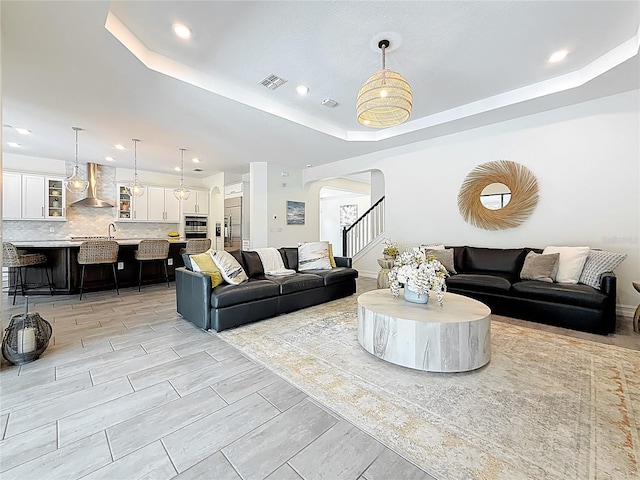 18203 Pine Hammock Blvd, Lutz, FL 33548 - living room featuring arched walkways, a tray ceiling, recessed lighting, and stairway