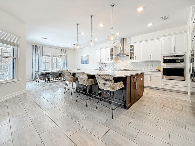 18203 Pine Hammock Blvd, Lutz, FL 33548 - kitchen with wall chimney range hood, a spacious island, backsplash, a sink, and stainless steel double oven