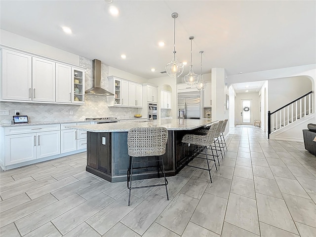 18203 Pine Hammock Blvd, Lutz, FL 33548 - kitchen with wall chimney range hood, stainless steel built in refrigerator, arched walkways, decorative backsplash, and white cabinets