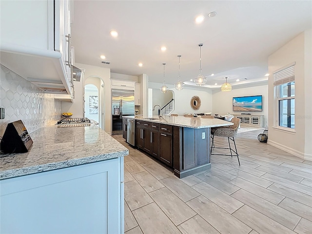 18203 Pine Hammock Blvd, Lutz, FL 33548 - kitchen with a sink, a breakfast bar area, decorative backsplash, a kitchen island with sink, and dark brown cabinetry