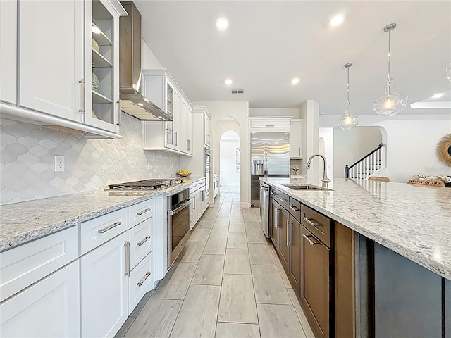 18203 Pine Hammock Blvd, Lutz, FL 33548 - kitchen featuring wall chimney exhaust hood, a sink, stainless steel appliances, arched walkways, and glass insert cabinets