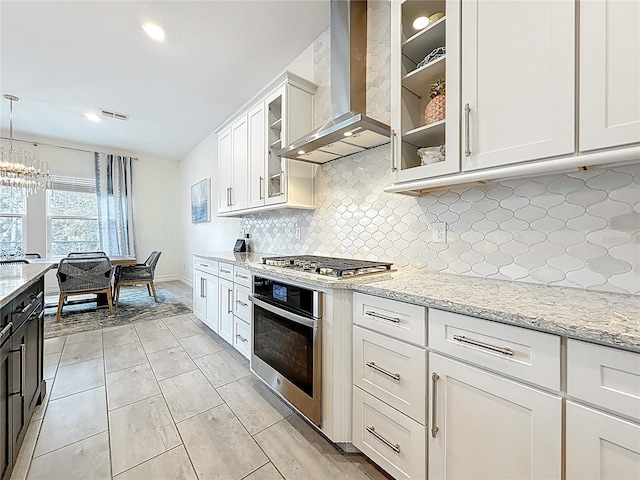 18203 Pine Hammock Blvd, Lutz, FL 33548 - kitchen featuring stainless steel appliances, wall chimney exhaust hood, tasteful backsplash, white cabinetry, and light stone counters