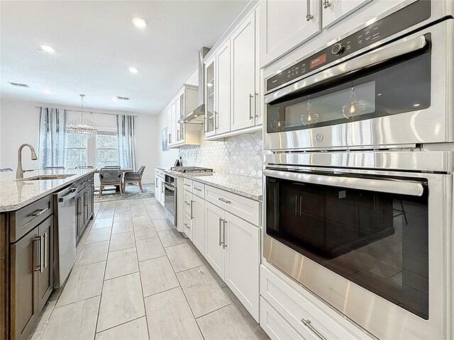 18203 Pine Hammock Blvd, Lutz, FL 33548 - kitchen with stainless steel appliances, a sink, tasteful backsplash, white cabinets, and light stone counters