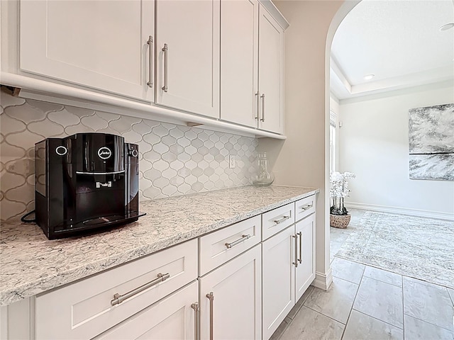 18203 Pine Hammock Blvd, Lutz, FL 33548 - kitchen featuring tasteful backsplash, arched walkways, white cabinets, light stone countertops, and baseboards