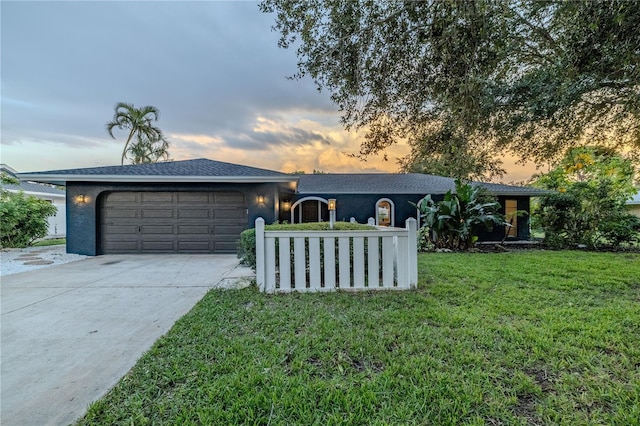 view of front of property featuring a lawn, stucco siding, driveway, and a garage