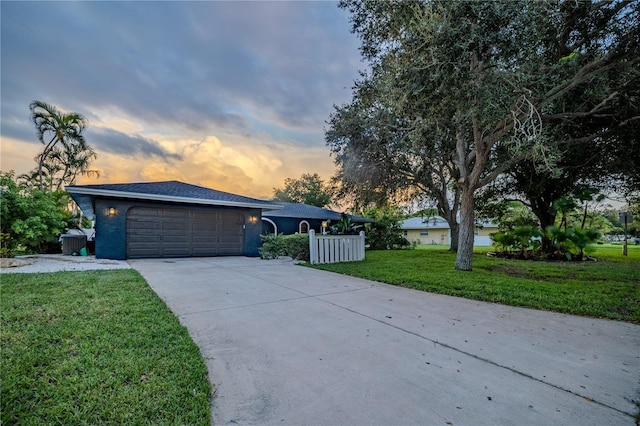 view of front of property featuring fence, an attached garage, stucco siding, a lawn, and driveway