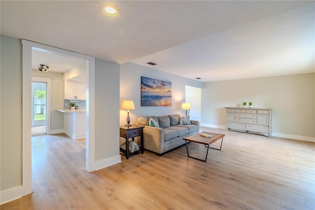living area with visible vents, light wood finished floors, and baseboards