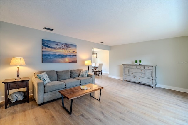 living room featuring baseboards, visible vents, and light wood finished floors