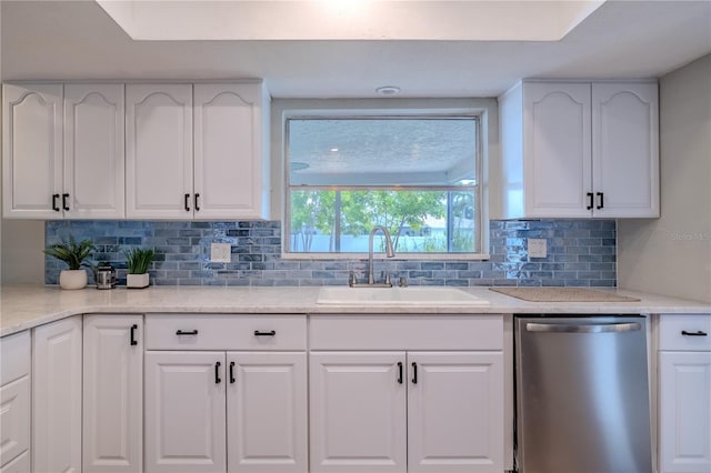 kitchen featuring white cabinets, decorative backsplash, a sink, and dishwasher