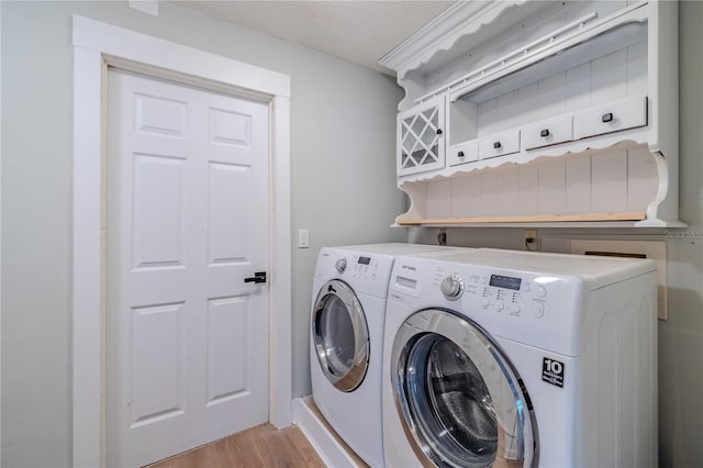laundry room with laundry area, washer and clothes dryer, and light wood-style floors