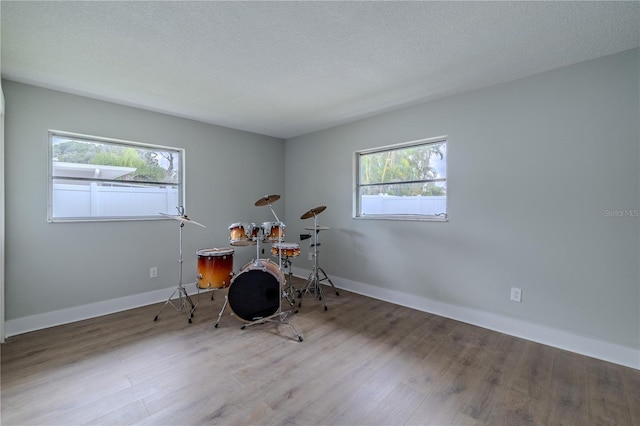 rec room featuring baseboards, a textured ceiling, and wood finished floors