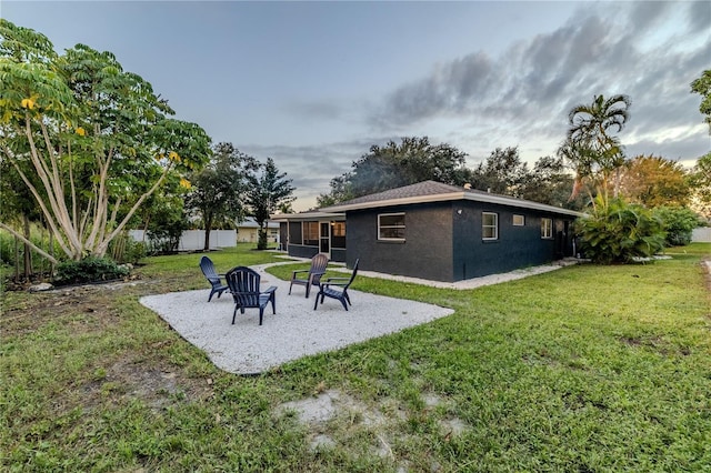 rear view of property featuring fence, stucco siding, a sunroom, a lawn, and a patio